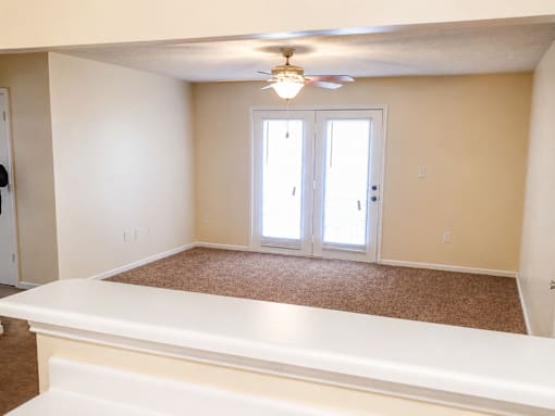 A room with a carpeted floor and a ceiling fan.