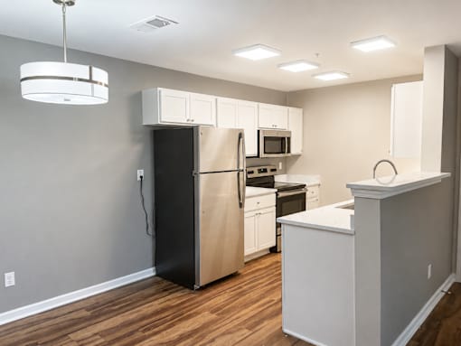 A kitchen with white cabinets and a black refrigerator.