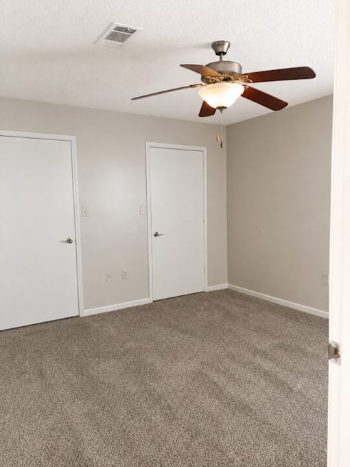 A room with a ceiling fan and carpeted floor.