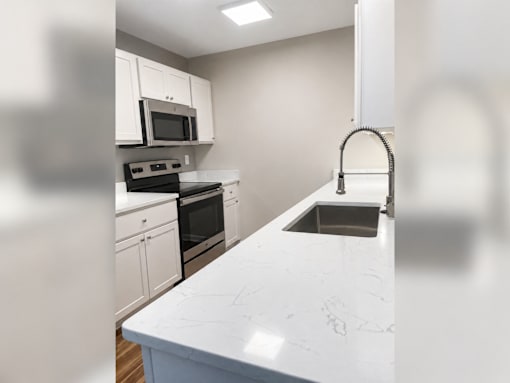 A kitchen with white cabinets and a marble countertop.