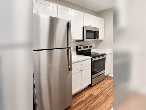 A kitchen with a stainless steel refrigerator, microwave, oven, and cabinets.
