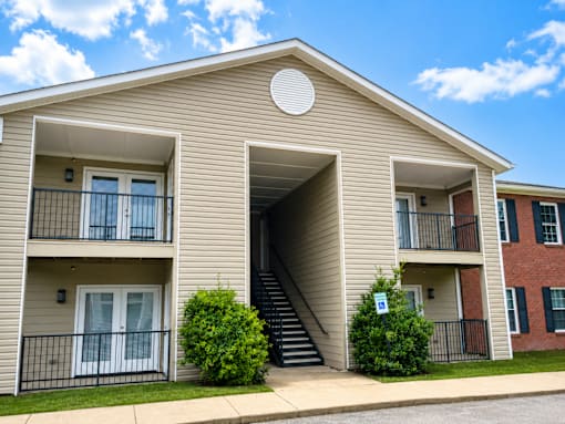 A beige apartment building with a blue sky and clouds in the background.