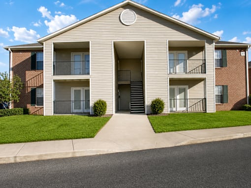 A two-story apartment building with a front lawn and a driveway.