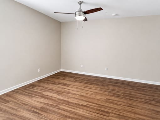A room with a ceiling fan and wooden flooring.