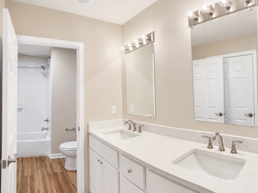 A white bathroom with a toilet, sink, and mirror.