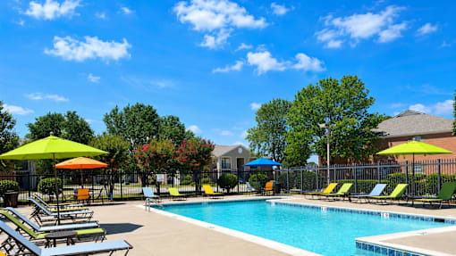 A pool area with sun loungers and umbrellas.