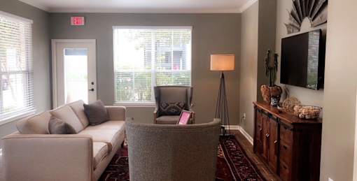A living room with a couch, chair, and a television.