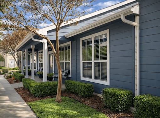 A blue house with white trim and a tree in front.