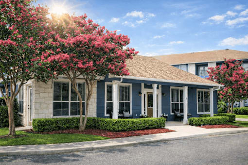 A house with a blue exterior and a red flowering tree in front.