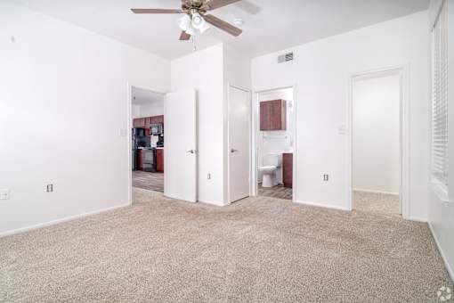 A room with a ceiling fan and carpeted floor.