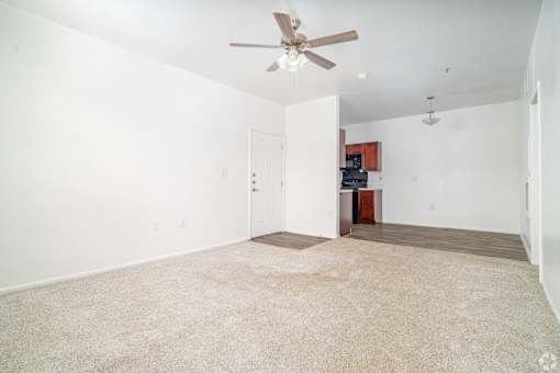 A room with a ceiling fan and carpeted floor.