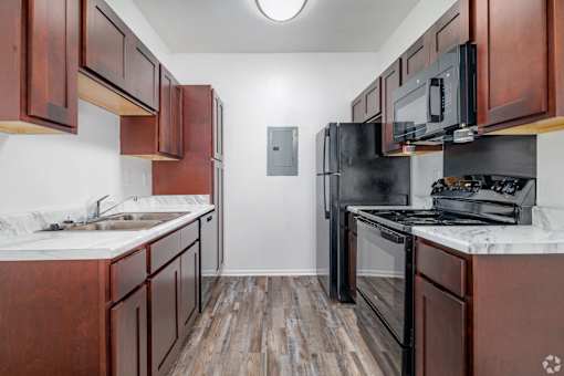 A kitchen with dark wood cabinets and black appliances.