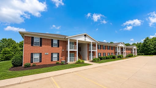 A long brick building with a white roof and a parking lot in front.
