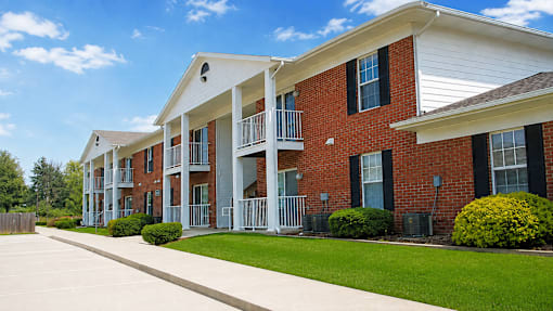 A row of red brick apartment buildings with white trim and black shutters.