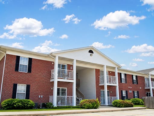 A red brick apartment building with a white roof and a balcony.