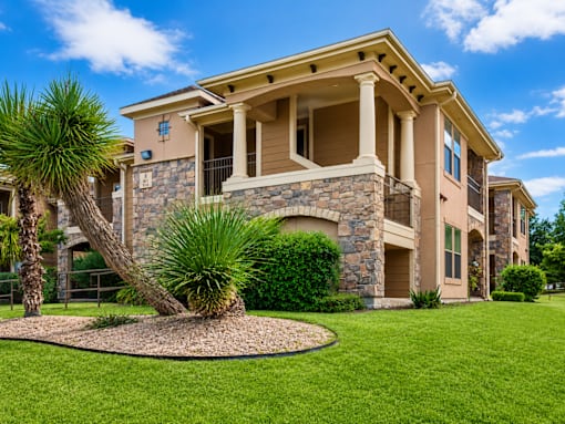 A large house with a stone and wood exterior and a landscaped front yard.