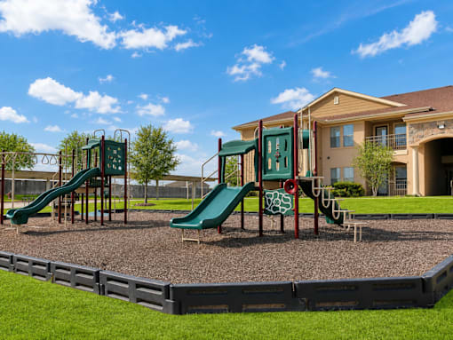 A playground with a green slide and a red and green slide.