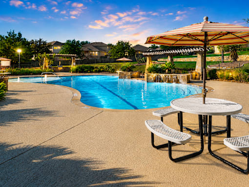 A pool with a table and chairs and umbrella.