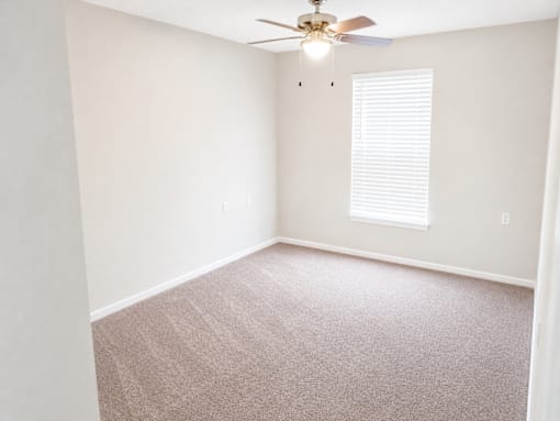 A room with a ceiling fan and a window with blinds.