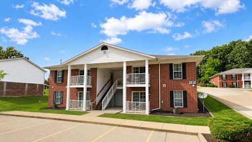 A red brick building with a white porch and a white roof.