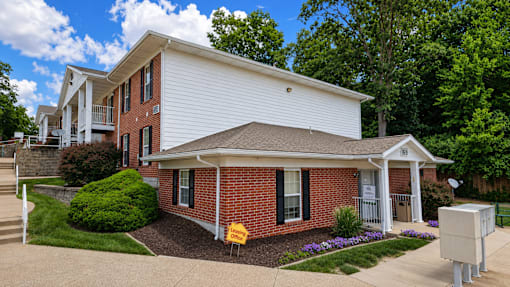 A white house with a red brick front and a driveway.