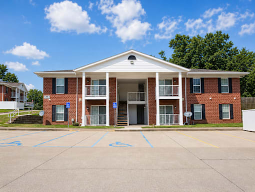 A red brick building with a white roof and a parking lot in front.