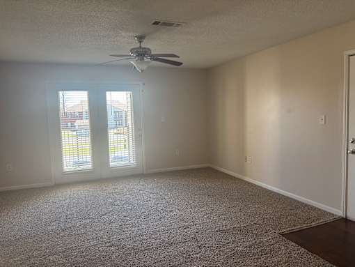 A room with a ceiling fan and carpeted floor.