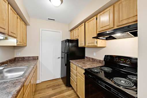 A kitchen with wooden cabinets and a black stove top oven.