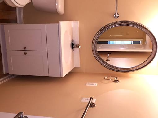A bathroom with a toilet, sink and mirror.