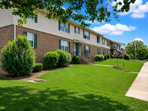 Apartment building with green bushes in front.