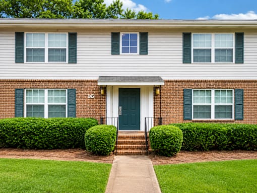 A house with a green door and two windows with green shutters.
