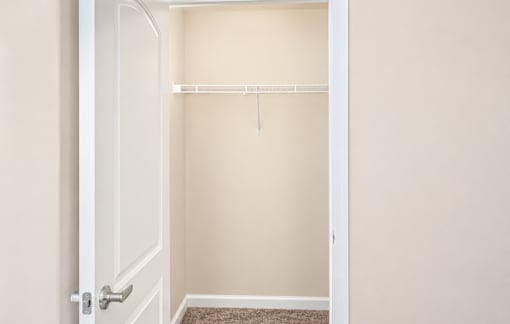 A white door is open to a room with a shelf and a rug on the floor.