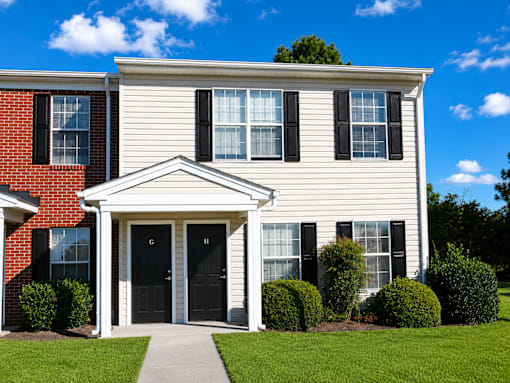 A house with a red brick section and a white siding section with a black door and windows.