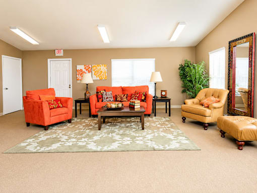 A living room with orange chairs and a rug.