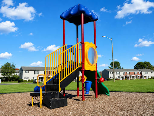A playground with a blue and yellow slide and a red and yellow staircase.