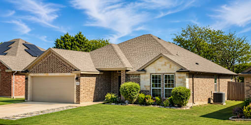 A house with a brown brick exterior and a grey garage door.