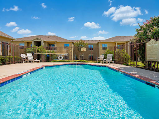 A swimming pool in front of a building with a fence around it.