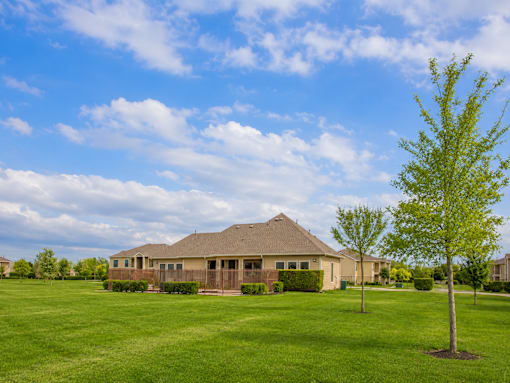 A house with a brown roof and a green lawn in front of it.