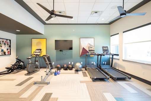 A gym with a variety of equipment including treadmills, exercise bikes, and weights.