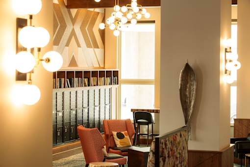 A room with a chair and a table with a lamp on it.
