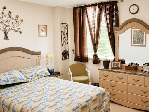 A bedroom with a bed, chair, and a clock on the wall.