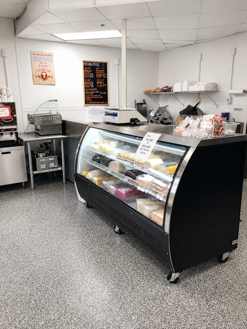 A display case filled with pastries sits in the middle of a clean, white-walled bakery.