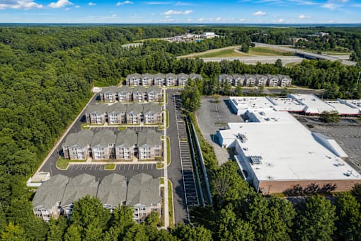 A bird's eye view of a residential area with apartment buildings and a parking lot.