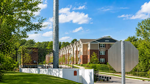 A tall metal pole stands in front of a building with a white stop sign attached to it.
