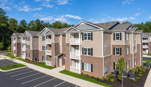 A large apartment complex with a parking lot in front.