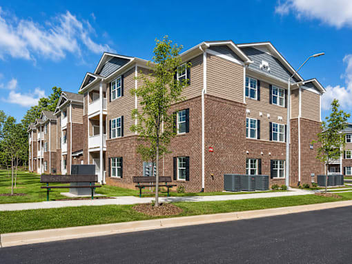 A large brick apartment building with a green lawn in front.