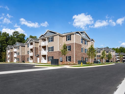 A large apartment complex with a parking lot in front.