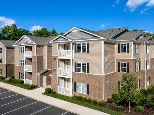 Apartment complex with a parking lot in front.