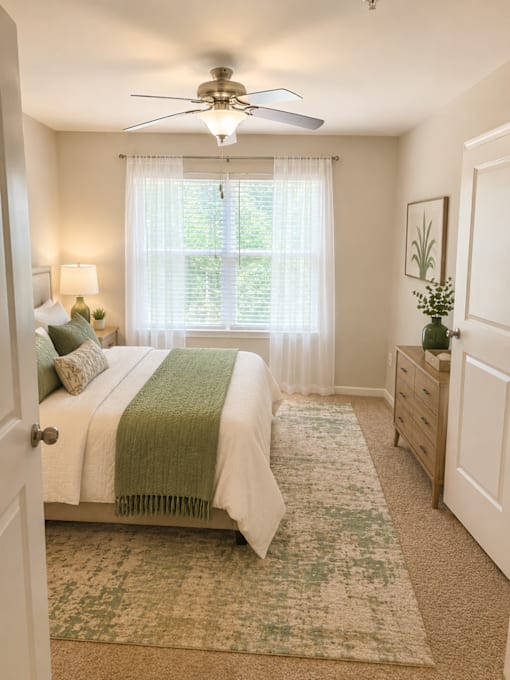 A bedroom with a bed, nightstand, and window with curtains.