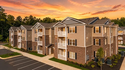 Apartment complex with a parking lot in front.